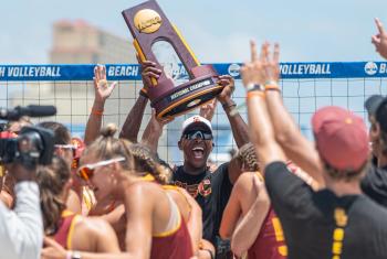 Coach and team celebrating win at NCAA Beach Volleyball Championship in Gulf Shores