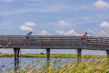 People biking on a boardwalk across Lake Shelby in Gulf State Park