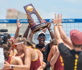 Coach and team celebrating win at NCAA Beach Volleyball Championship in Gulf Shores