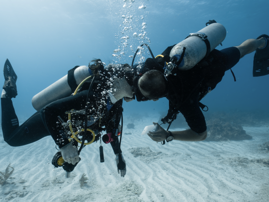 Scuba Divers kissing underwater, unique proposal idea at the beach