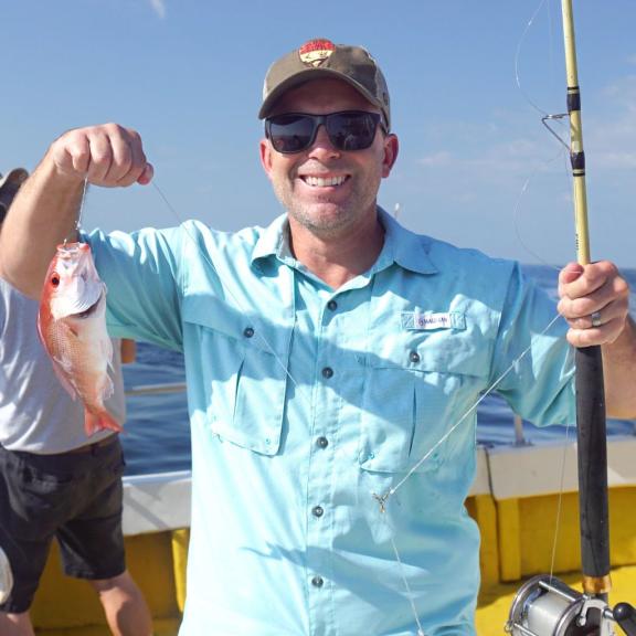 Man holding a vermillion snapper on a charter boat in Orange Beach