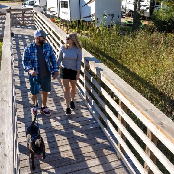 Couple walking dog on boardwalk in Gulf Shores RV campground
