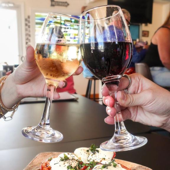 Friends clinking wine glasses at Lauria's by the Beach in Gulf Shores