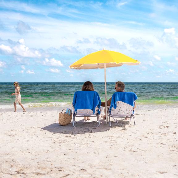 Couple in beach chairs watching their kids play by the water on the beach in Gulf Shores