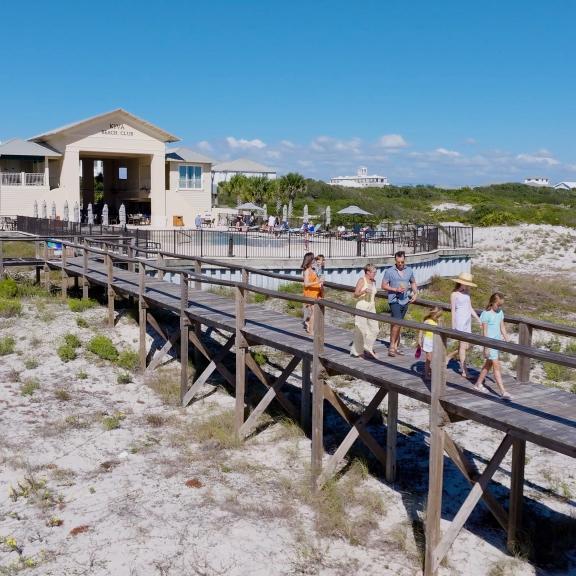 Family walking along a boardwalk towards the beach at Kiva Dunes Resort in Fort Morgan