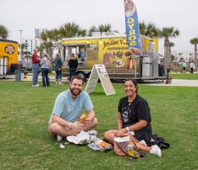 Couple sitting on the green lawn at Gulf Place during the Coastal Alabama Food Truck Festival in Gulf Shores